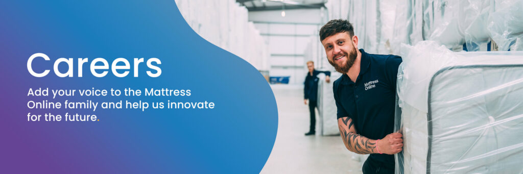 A Mattress Online warehouse staff member smiling while moving a mattress