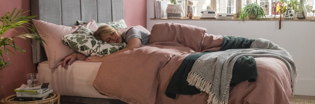 Woman sleeping on a bed with pink bedding